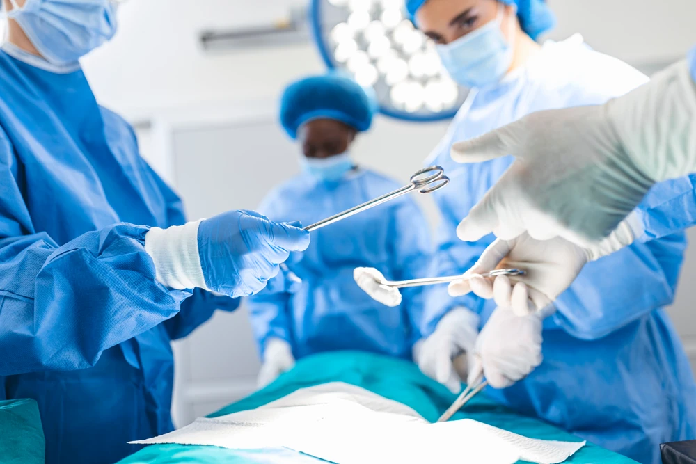 Low Angle Shot in the Operating Room, Assistant Hands out Instruments to Surgeons During Operation.