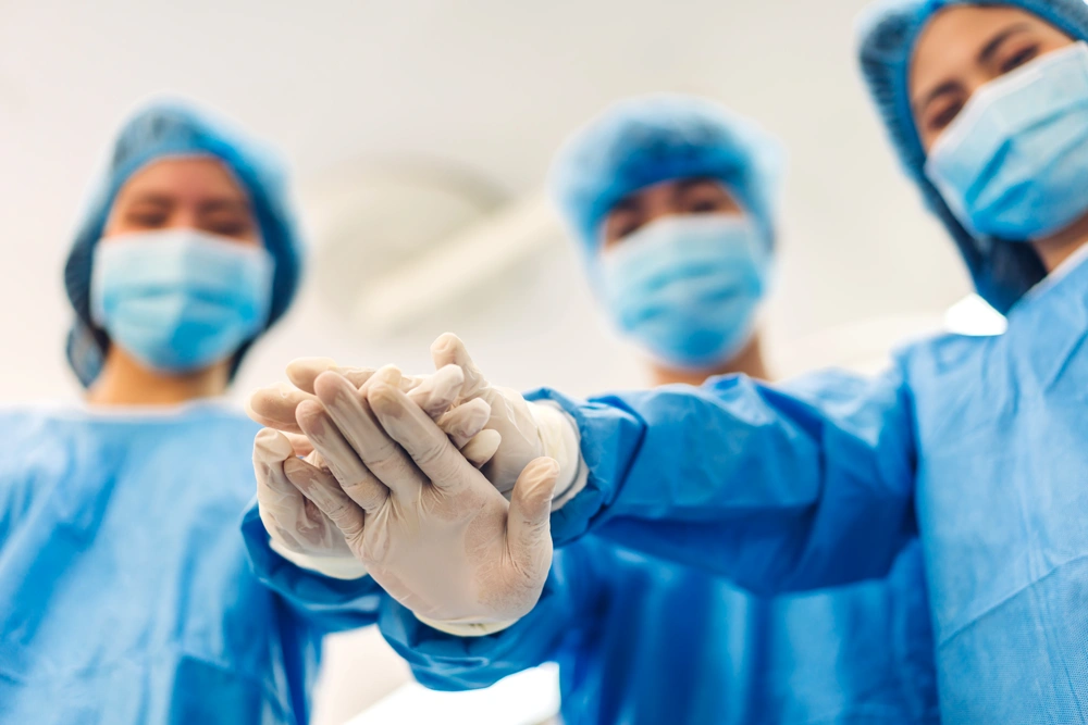 Portrait of group successful professional anesthesiologist doctor medical team and assistant stand celebrating success putting and joining their hands teamwork together in modern hospital